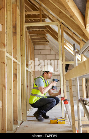 Construction Worker Using Drill On House Build Stock Photo