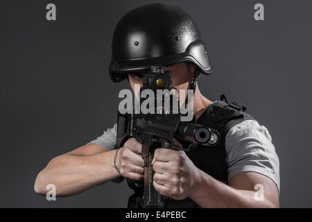 Security, paintball sport player wearing protective helmet aiming pistol ,black armor and machine gun Stock Photo