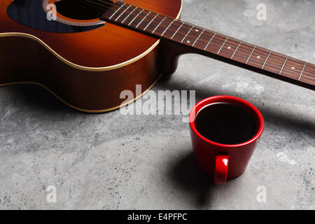 A hot cup of coffee and a guitar on a concrete surface. Stock Photo