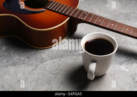 A hot cup of coffee and a guitar on a concrete surface. Stock Photo