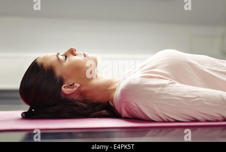 Close up image of young woman lying on a yoga mat with her eyes closed in meditation. Stock Photo
