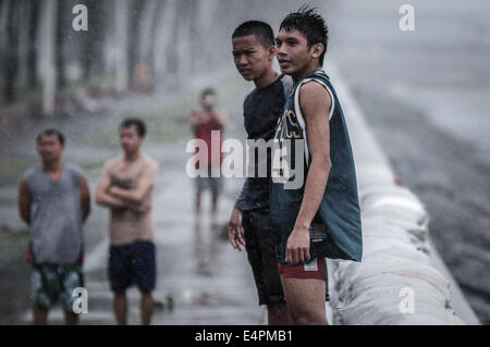 Manila, Philippines. 16th July, 2014. Pedestrians walk past uprooted trees along a highway as Typhoon Rammasun barrels across Manila on July 16, 2014. Typhoon Rammasun shut down the Philippine capital on July 16 as authorities said the first major storm of the country's brutal rainy season claimed at least four lives and forced hundreds of thousands to evacuate. Credit:  George Calvelo/NurPhoto/ZUMA Wire/Alamy Live News Stock Photo