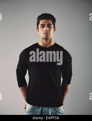 Portrait of handsome young hispanic guy posing. Smart male fashion model posing on grey background. Stock Photo