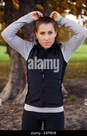 Portrait of beautiful young woman runner standing in park looking at camera. Female fitness model outdoors. Stock Photo