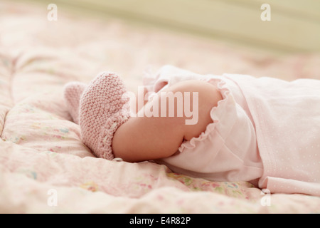 Legs of a baby lying down on quilt wearing knitted booties, 6 weeks Stock Photo