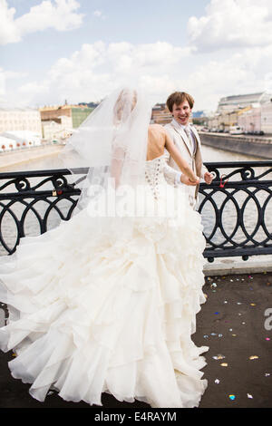 Bride and groom pose on the The Luzhkov Bridge, Wedding Bridge, or Bridge of Kisses, over the Moskva River, Moscow, Russia Stock Photo