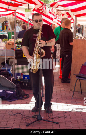 Male Saxophonist playing in Rugby Town Centre on Market Day. Stock Photo
