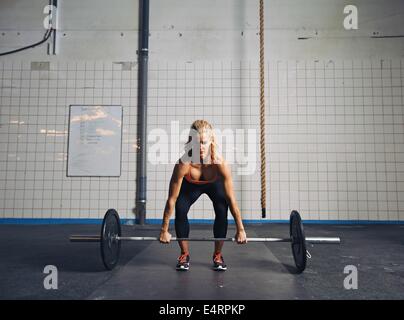 Strong young woman lifting heavy weights at gym. Fitness female doing crossfit workout. Stock Photo