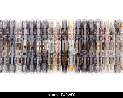 A stacked row of mixed compact  audio cassettes edge on, some showing tape, others tape leader, all in a variety of colours Stock Photo