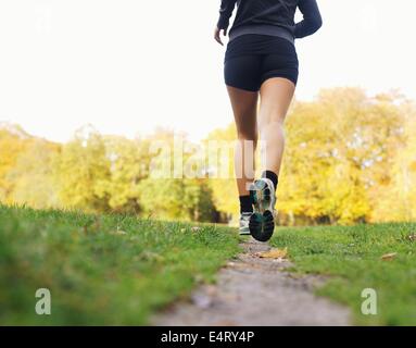 Rear view of woman athlete jogging in park. Female fitness model running outdoors Stock Photo