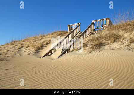 Sand-covered stairway to a public beach in Nags Head on the Outer Banks of North Carolina against a bright blue sky Stock Photo