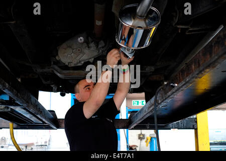 male employee removes an old car exhaust system and replaces it with a new one Stock Photo