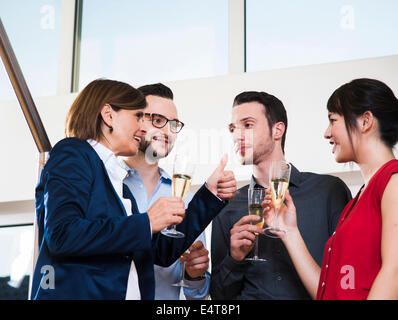 Mature businesswoman toasting group of young business people with glasses of champagne, Germany Stock Photo