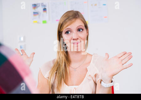 Close-up of young, blond businesswoman making hand gesture in meeting in office, Germany Stock Photo