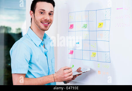 Close-up portrait of young businessman standing beside whiteboard in office, Germany Stock Photo