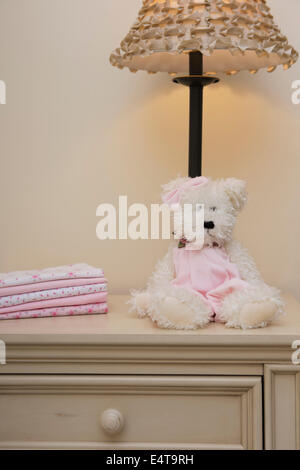 Stack of Baby Blankets on Dresser next to Teddy Bear and Lamp in Nursery Stock Photo