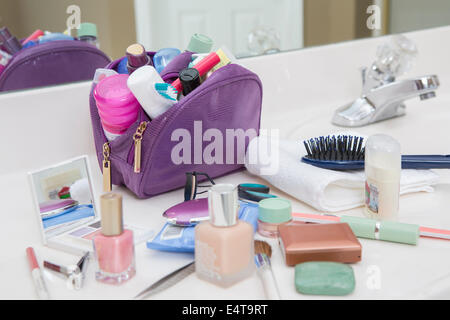 Women's Toiletry Travel Bag on Bathroom Counter filled with Personal Hygiene Products Stock Photo