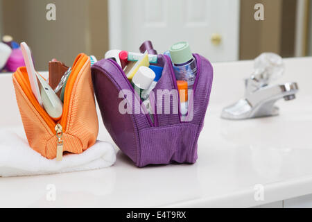 Women's Toiletry Travel Bag on Bathroom Counter filled with Personal Hygiene Products Stock Photo