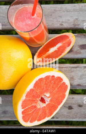 Pieces of grapefruit and a glass of fresh squeezed grapefruit juice on the wooden surface.top view Stock Photo