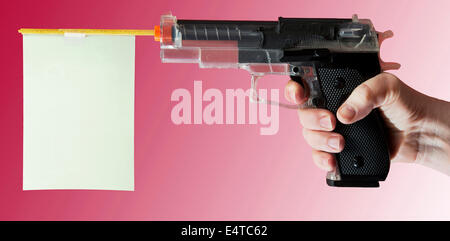 Close-up of woman's hand pointing toy gun on pink background, studio shot