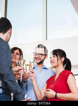 Mature businesswoman toasting group of young business people with glasses of champagne, Germany Stock Photo