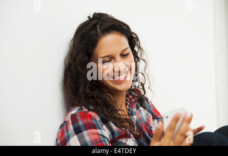 Close-up portrait of teenage girl looking at cell phone and smiling, Germany