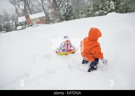 Boy Pulling his little Sister on Sled through Snow, Maryland, USA Stock Photo