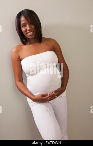 Portrait of Pregnant Woman holding Belly, Studio Shot Stock Photo
