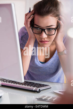Close-up of young woman using laptop computer, looking confused, studio shot Stock Photo