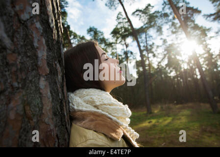 Young Woman Leaning against Tree Trunk, Mannheim, Baden-Wurttemberg, Germany Stock Photo