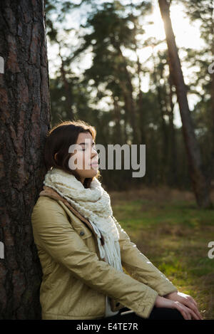 Young Woman Leaning against Tree Trunk, Mannheim, Baden-Wurttemberg, Germany Stock Photo