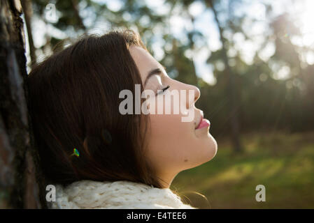 Young Woman Leaning against Tree Trunk, Mannheim, Baden-Wurttemberg, Germany Stock Photo