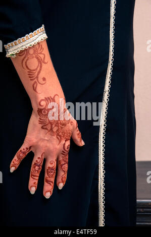 Woman standing with close-up of arms and hand painted with henna in arabic style, wearing black, arabic, muslim dress Stock Photo