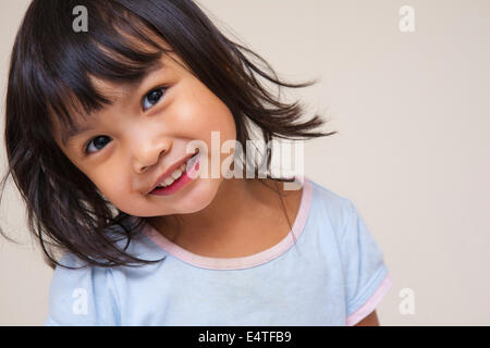 Close-up portrait of Asian toddler girl, looking at camera and smiling, studio shot on white background Stock Photo