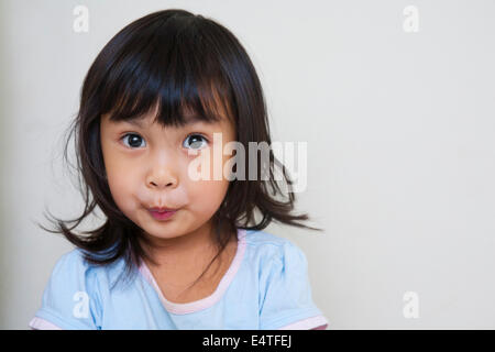 Close-up portrait of Asian toddler girl, looking at camera with surprised expression, studio shot on white background Stock Photo