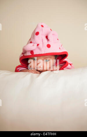 Portrait of two week old, newborn Asian baby girl in pink polka dot hooded jacket, studio shot on white background Stock Photo