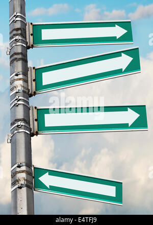 Arrow signs on a pole, showing different directions against sky Stock Photo