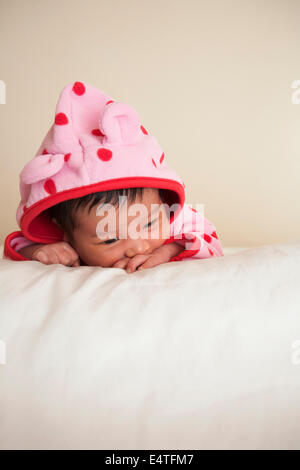 Portrait of two week old, newborn Asian baby girl in pink polka dot hooded jacket, studio shot on white background Stock Photo
