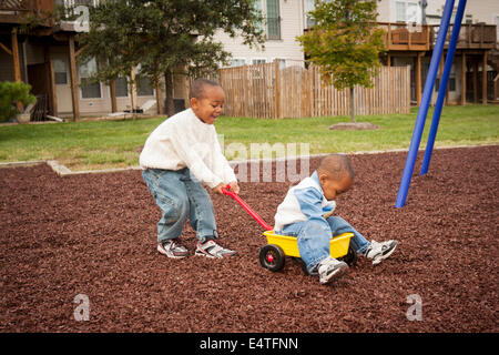 Boy Pulling Brother in Wagon at Playground, Maryland, USA Stock Photo