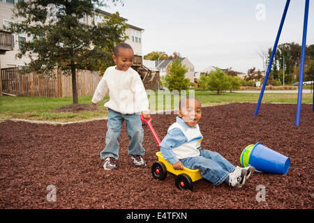 Boy Pulling Younger Brother in Wagon at Playground, Maryland, USA Stock Photo