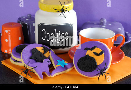 Happy Halloween party trick or treat purple and orange cookies with spiders and cookie jar. Stock Photo