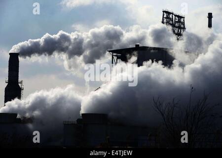 Feb. 9, 2014 - qingdao, CHN - 9, Feb, 2014. Qingdao, Shandong Province, China. After the snow, although it is Sunday, Chinese Sinopec Qingdao Refining and Chemical Co., Ltd. (Refinery) production is under way. Reporters see at the scene that tall chimneys emitting thick smoke, which cause severe air pollution. In 2013, part of the blown road cover debris that left since the 11.22 Sinope Qingdao Oil Pipeline Explosion was piled up on the Refinery's second phase vacant area. And the Zhang Gezhuang community, which is just across the road, is being demolished. Because of the Spring Festival, t Stock Photo