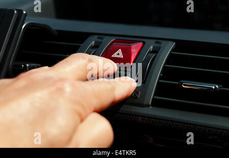 Hand pressing a hazard button, concept of safety on the roads Stock Photo