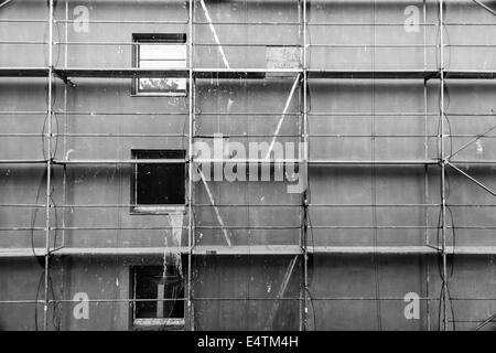 Scaffold on a block of flats in Czech Republic. 3 windows, 4 ladders & access hatches can be seen. All covered by a safety net Stock Photo