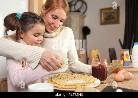 loving mother making crepes with little girl Stock Photo