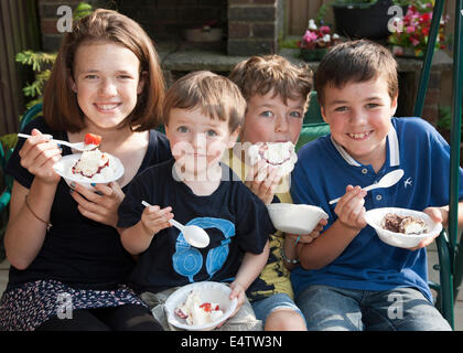Children eating ice cream and cakes at a family party Stock Photo