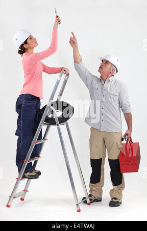 Two electricians working on ceiling lighting Stock Photo