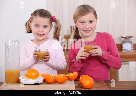 Two sisters making orange juice Stock Photo