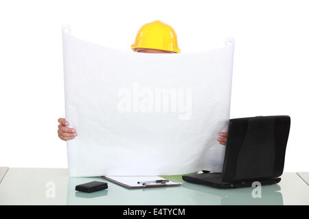 Architect sat at desk reading plans Stock Photo
