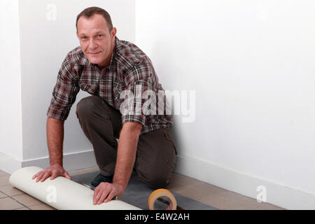 Man putting down linoleum flooring Stock Photo